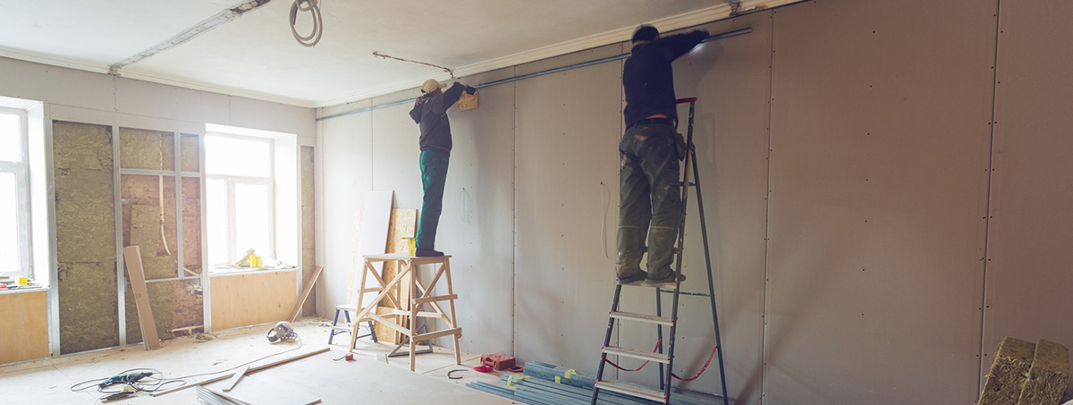 Workers installing drywall on new addition