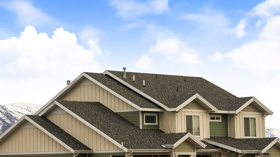 Close up picture of a residential roof against a blue sky.