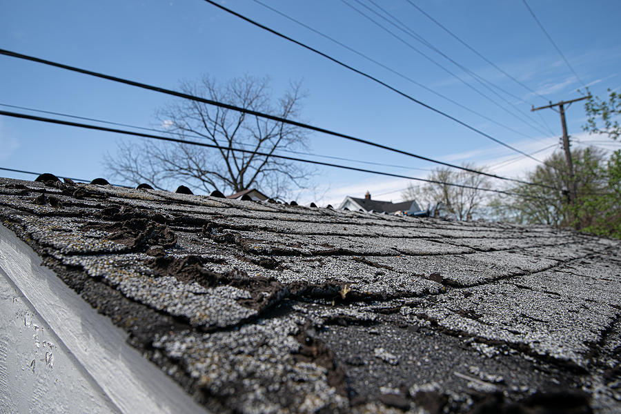 Close up photo of old shingles on a roof that needs to be replaced.