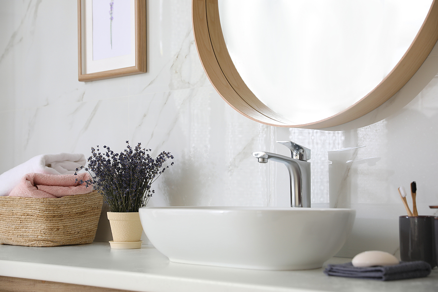 Bathroom counter with vessel sink, flowers and towels in bathroom interior. Idea for design.