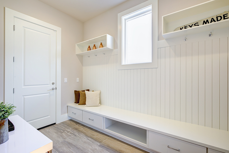 Pretty entrance. Renovated foyer with a wall clad in board and batten lined with an extra long built-in bench with storage drawers topped with white and brown pillows.