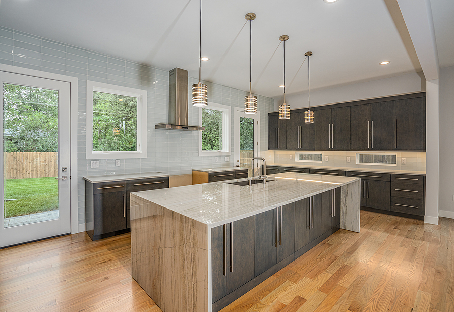 Newly remodeled kitchen with larg island, modern windows, and four pendant lights hanging over the island.