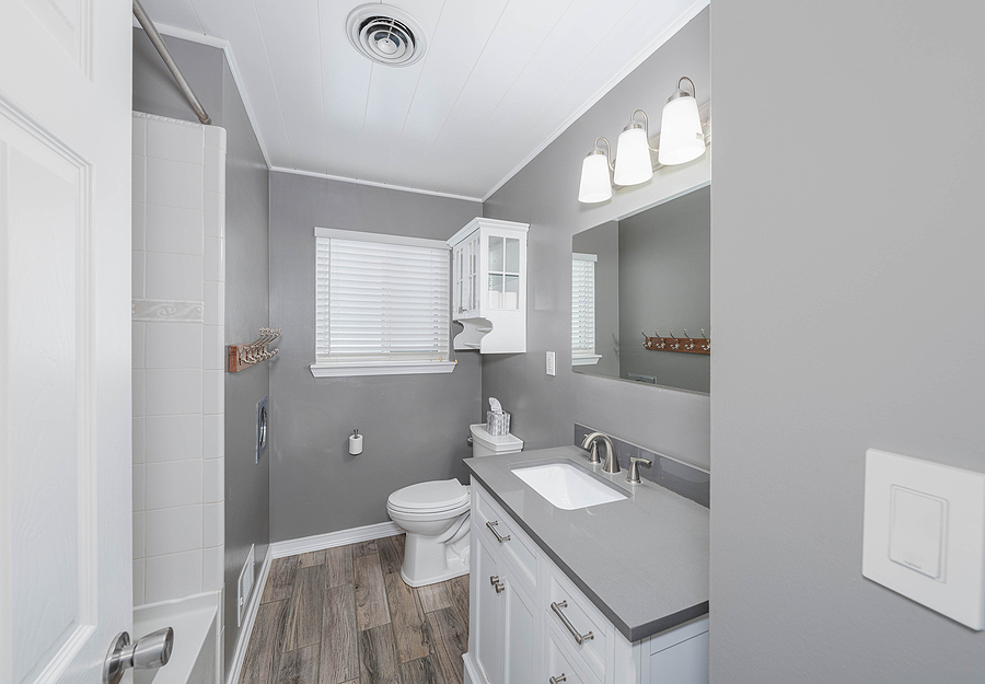 modern remodeled full bathroom with white cabinets, grey walls, and composite floors