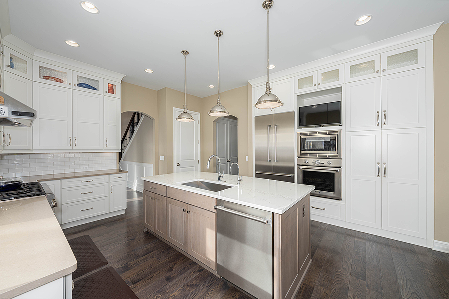 Modern kitchen renovation with large island and white cabinets.