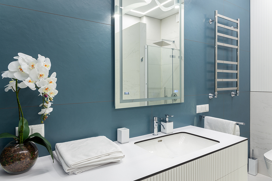 new bathroom with blue walls, white counters, furnishings, and decorations