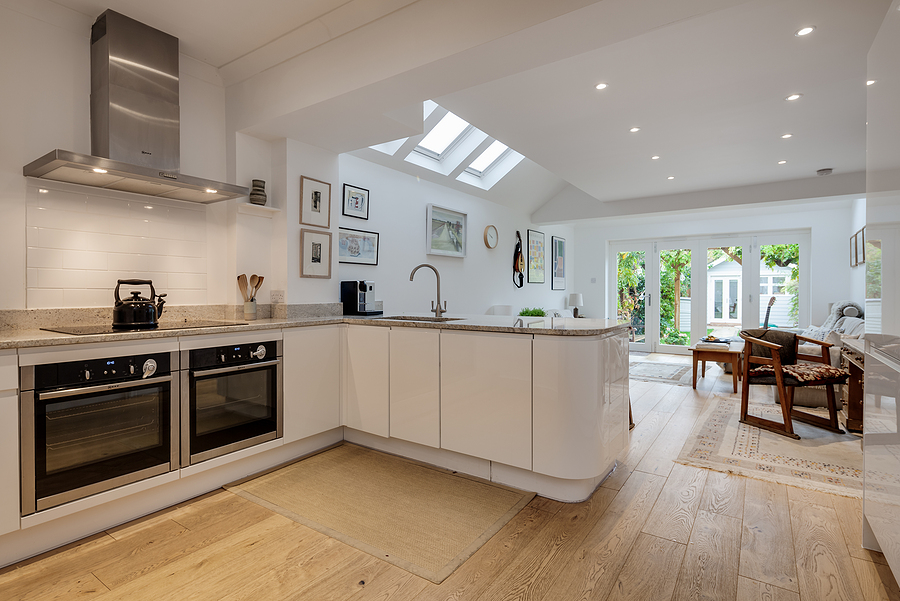 open concept kitchen and living room with wooden floors and white walls and cabinets