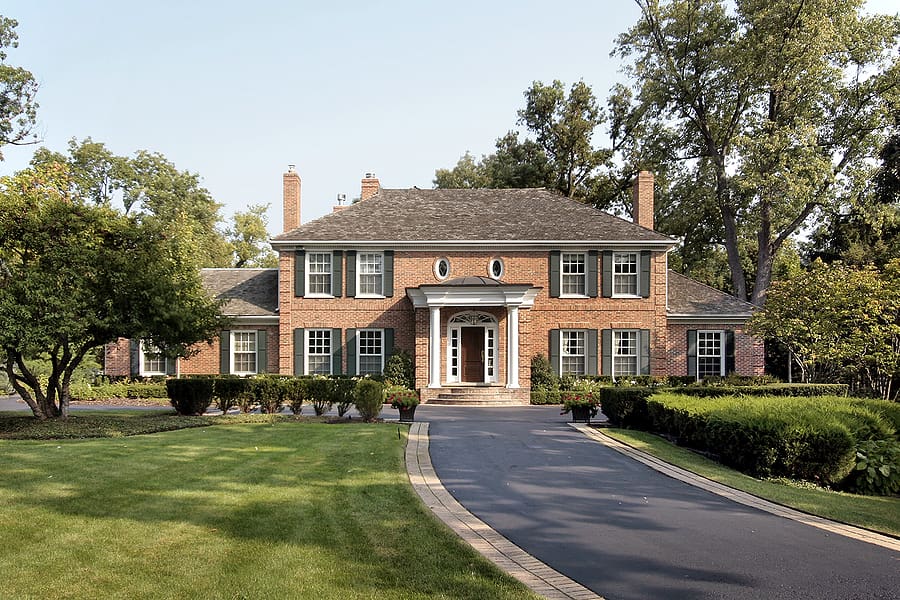 Large brick home with foliage and trees