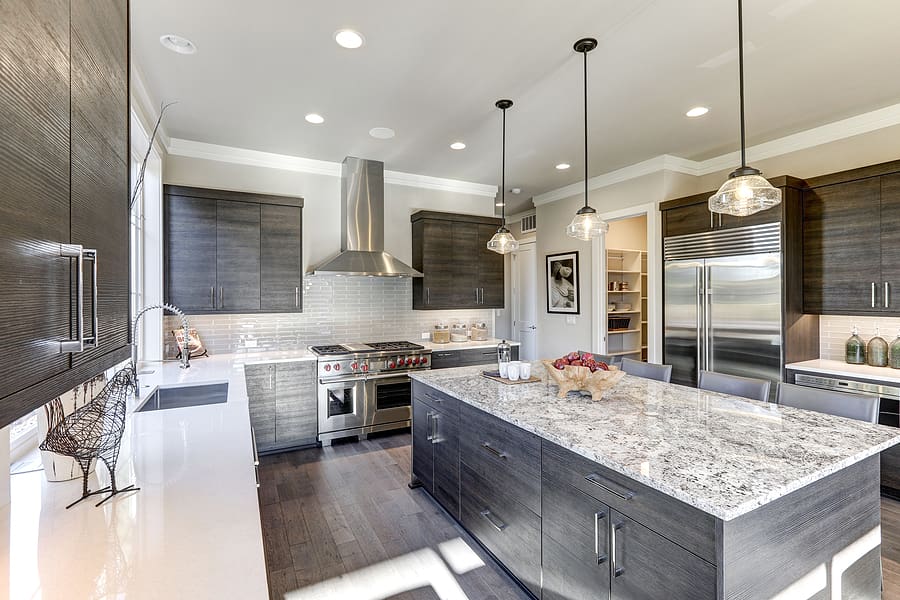 Modern kitchen featuring a gray kitchen island with white granite countertops with storage.