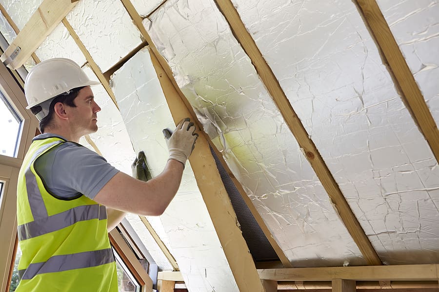 Worker fitting insulation into the roof of a home. 