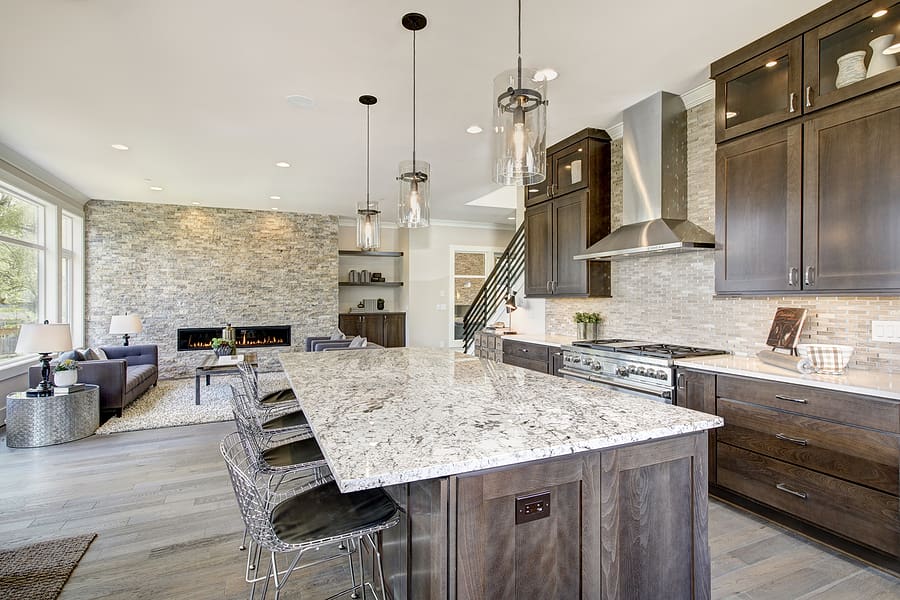 Luxury kitchen with large granite kitchen island and natural brown cabinets. 