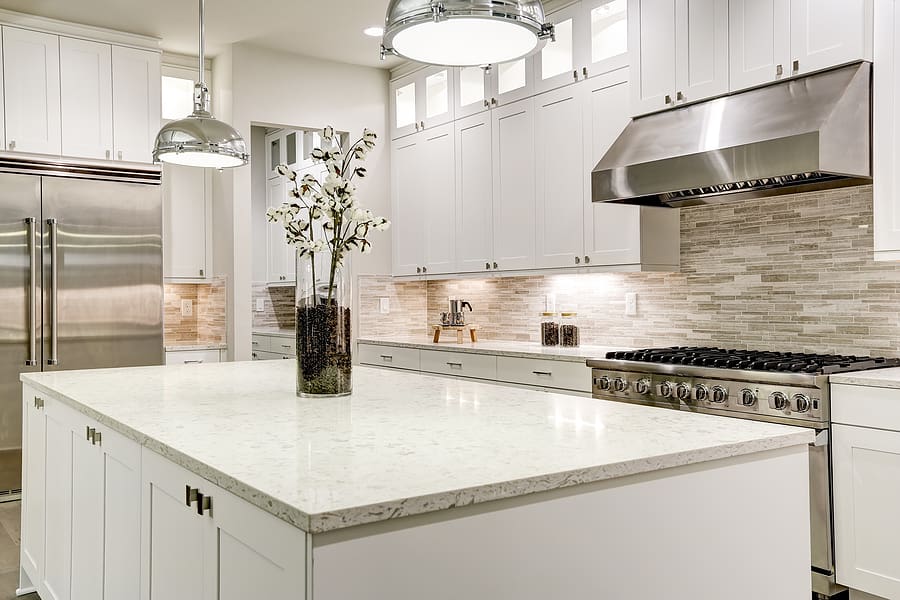 Updated modern kitchen featuring stainless steel appliances, a large kitchen island and white cabinets. 