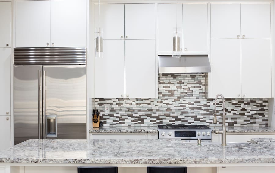 Renovated white kitchen with stylish backsplash with smart, stainless steel appliances. 