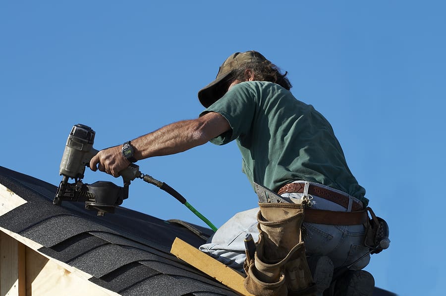 A roofer on a roof installing new shingles. 