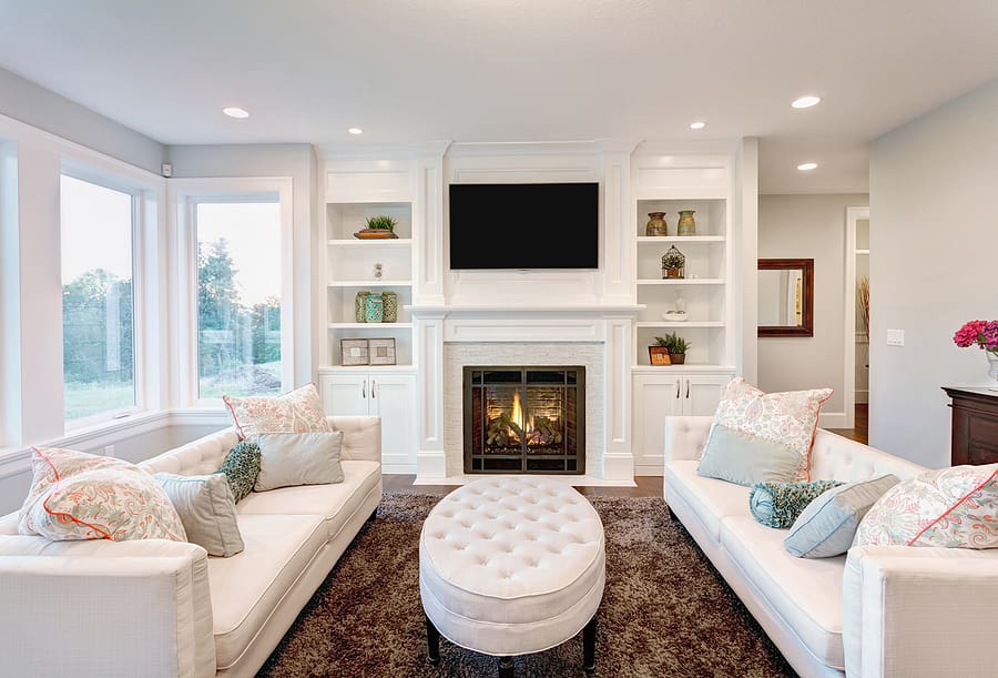 Renovated living room with white custom built shelves and a fireplace. 