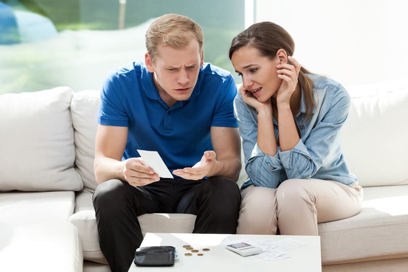 Married couple looking at ridiculously high energy bills caused by bad windows