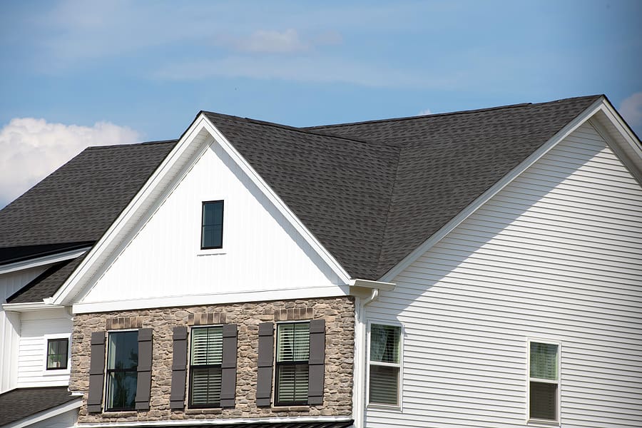 New asphalt roof with dark shingles on a modern white home. 